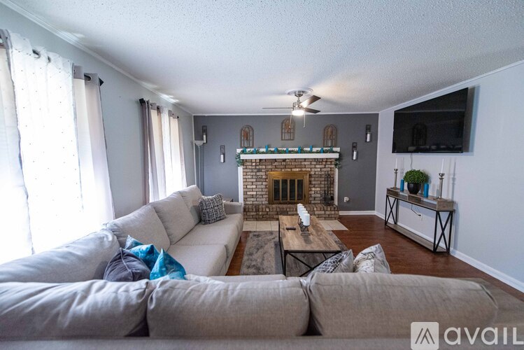 A living room with a grey couch and a fireplace.