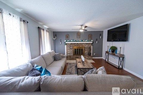 A living room with a grey couch and a fireplace.