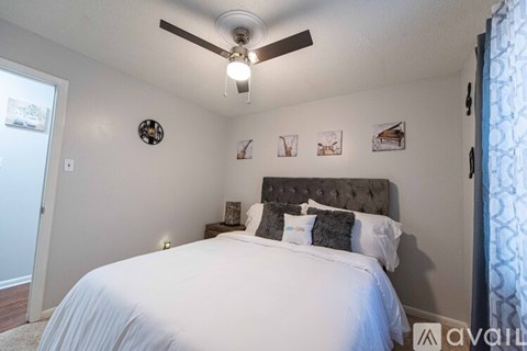 A bedroom with a large bed and a ceiling fan.