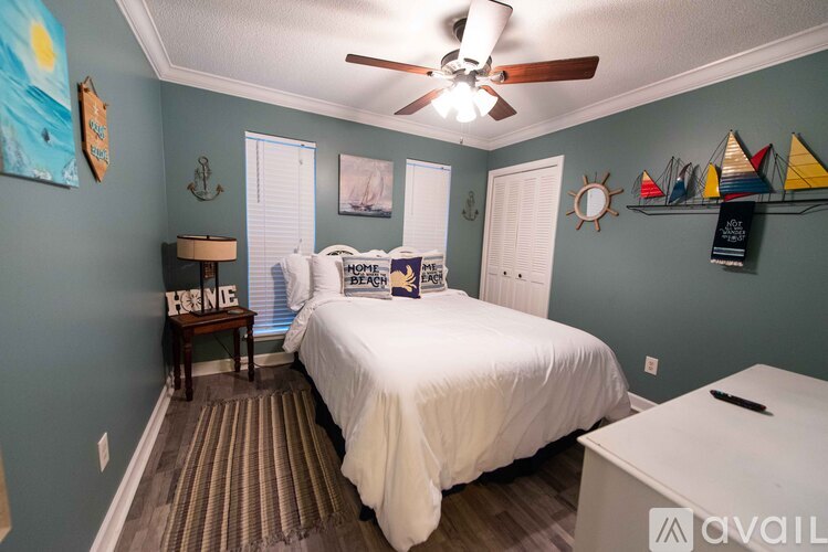 A bedroom with a white bed and a ceiling fan.