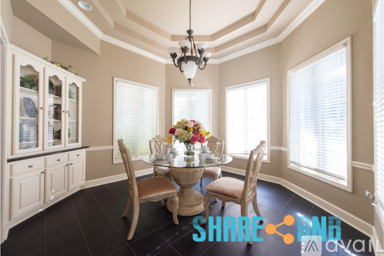 A dining room with a table set for four and a chandelier hanging from the ceiling.