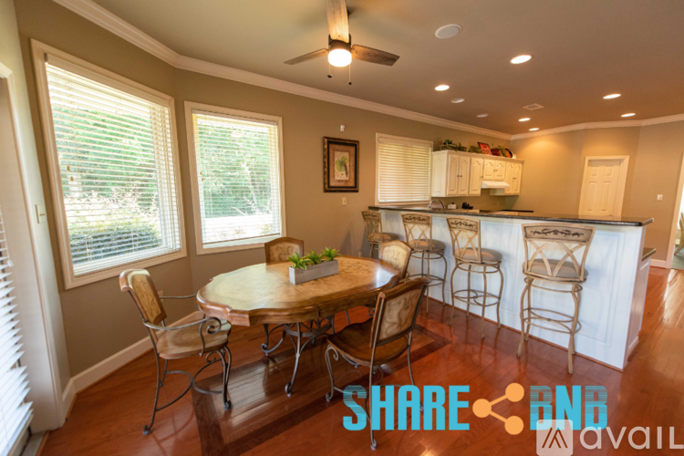 A dining room with a table set for four and a kitchen in the background.