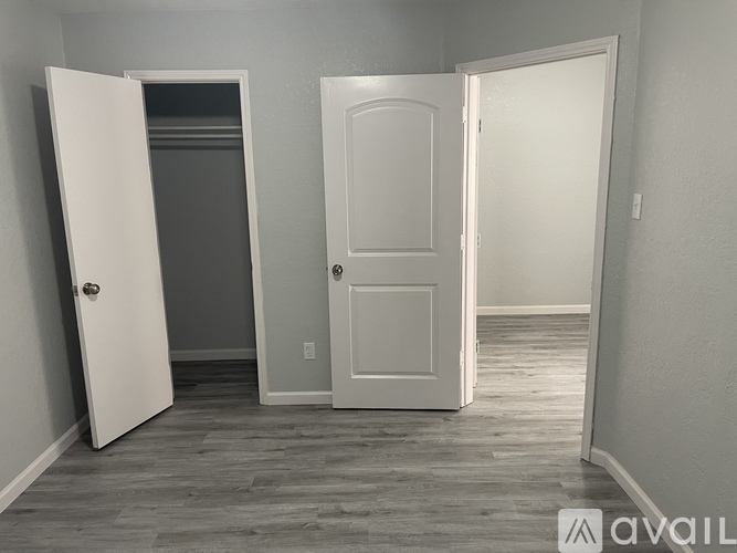 Three white doors in a room with wood flooring.