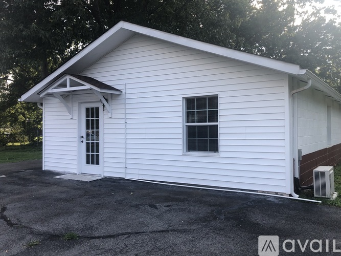 A small white house with a black roof and a window.