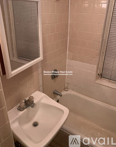 A white sink in a bathroom with a tub and a window.