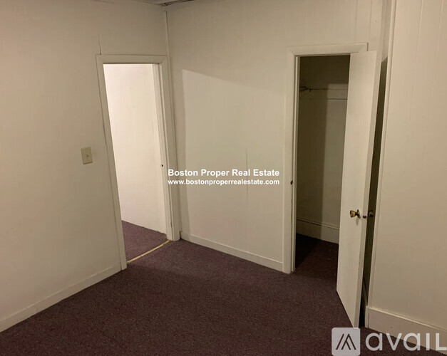 A room with a carpeted floor and two open doors.