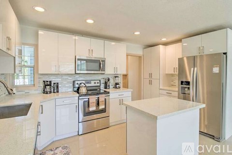 A modern kitchen with white cabinets and stainless steel appliances.