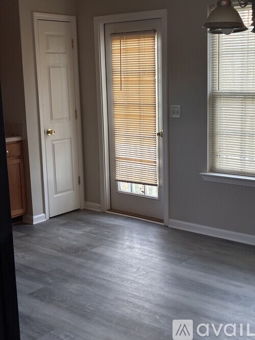 A room with a white door and a grey floor.