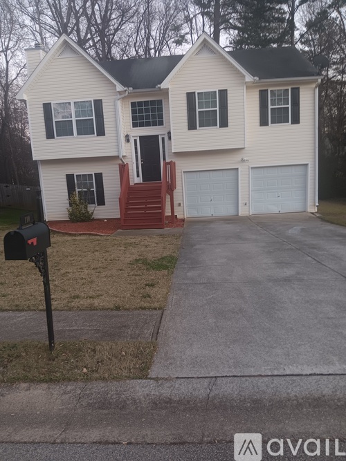 A two-story house with a red front door and a mailbox on the sidewalk.