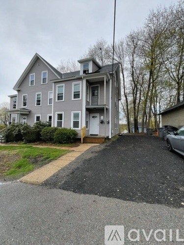 A grey two-story house with a driveway in front.
