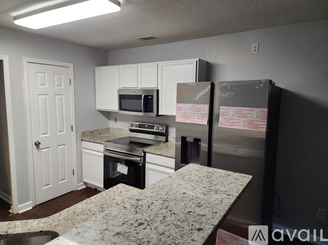 A kitchen with a granite countertop and a refrigerator with a box on it.