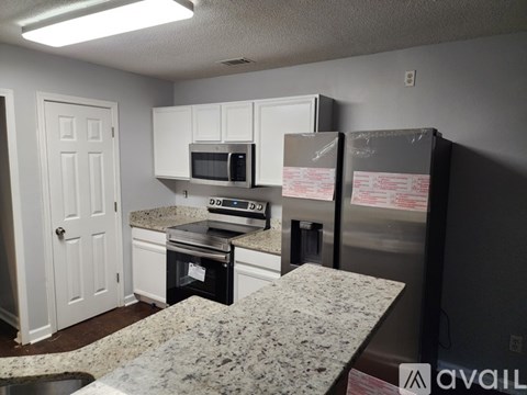 A kitchen with a granite countertop and a refrigerator with a box on it.