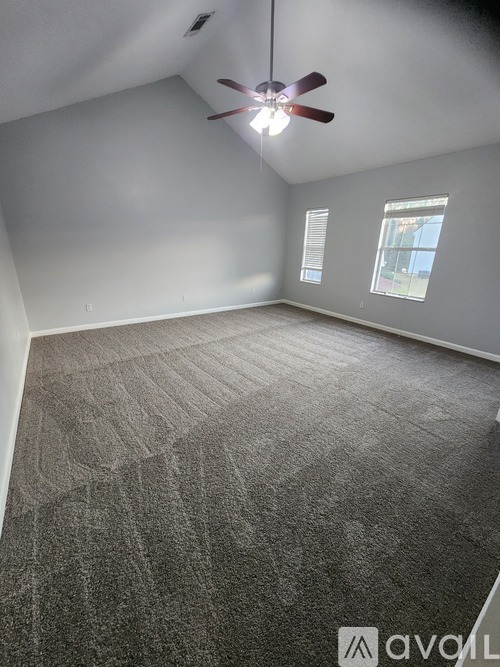 A room with a ceiling fan and carpeted floor.