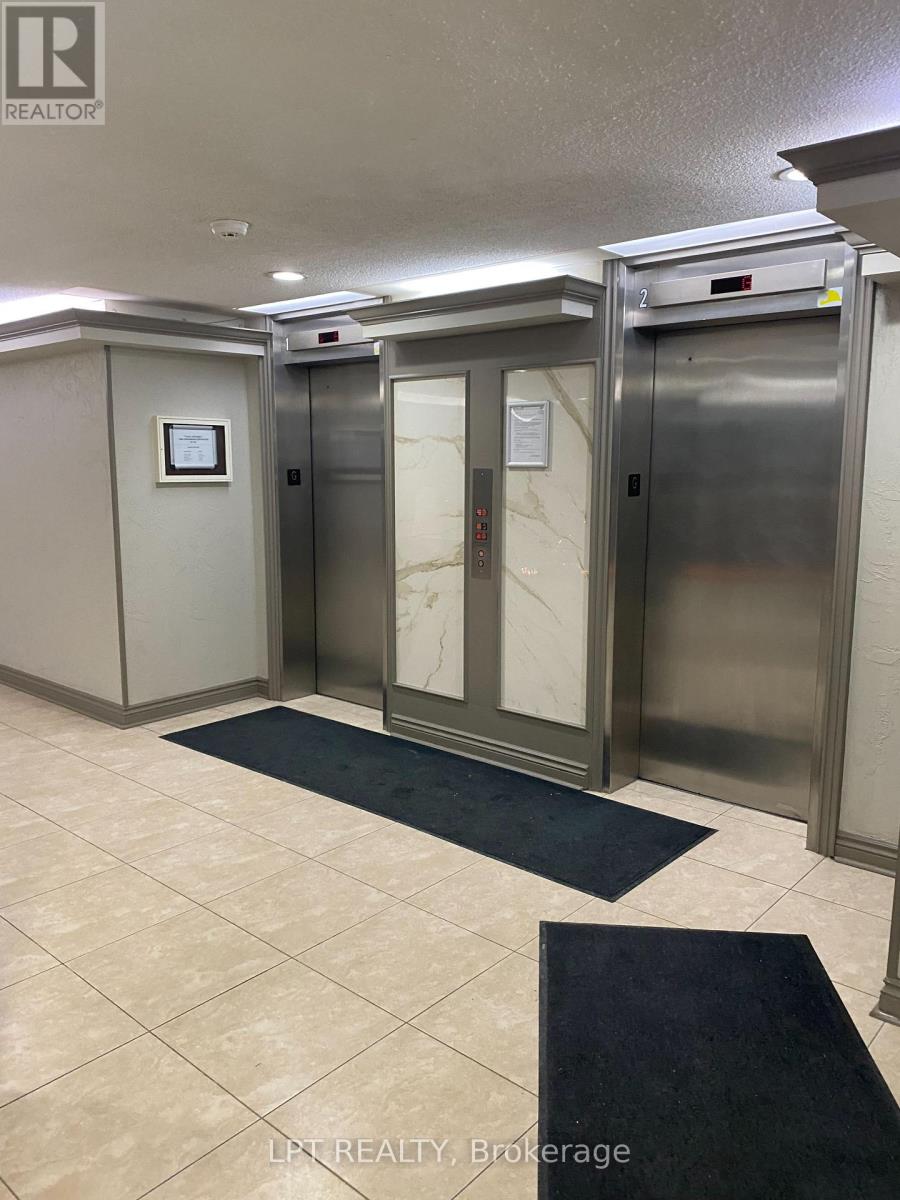 A hallway with two elevators and a sign that says LPF Realty Brokerage.