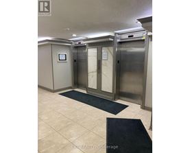 A hallway with two elevators and a sign that says LPF Realty Brokerage.