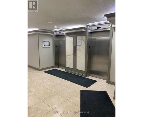 A hallway with two elevators and a sign that says LPF Realty Brokerage.