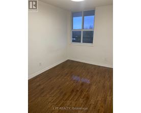 A room with wooden flooring and a window showing a blue sky.