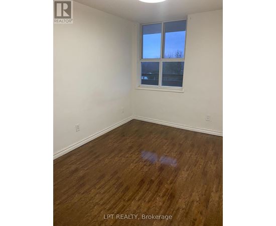 A room with wooden flooring and a window showing a blue sky.