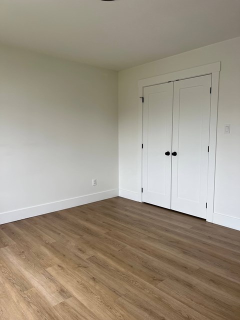 A room with a white door and wooden flooring.
