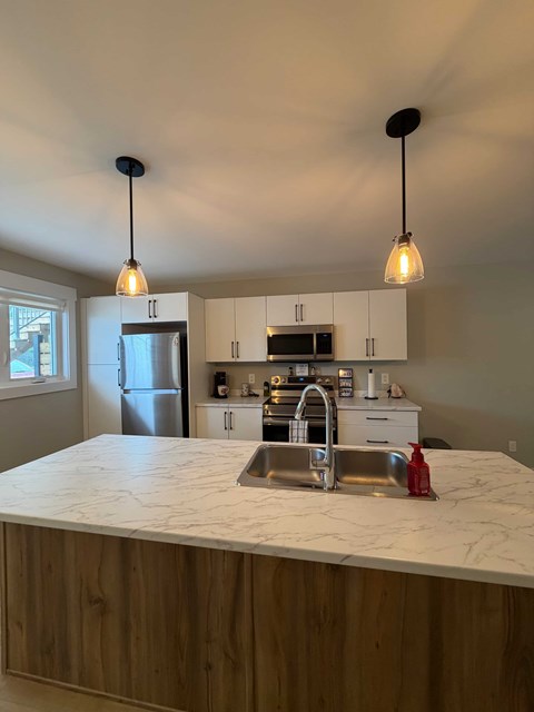 A kitchen with a marble countertop and wooden cabinets.