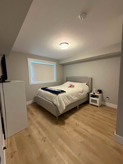 A bedroom with a bed, nightstand, and a window.