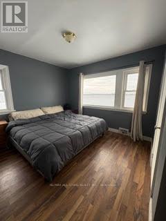 A bedroom with a bed, wooden floors, and a window.