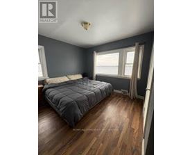 A bedroom with a bed, wooden floors, and a window.