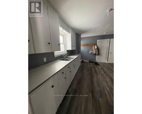 A kitchen with white cabinets and a wooden floor.