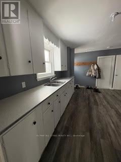 A kitchen with white cabinets and a wooden floor.