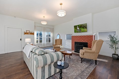 A living room with a striped couch, a fireplace, and a television mounted above it.