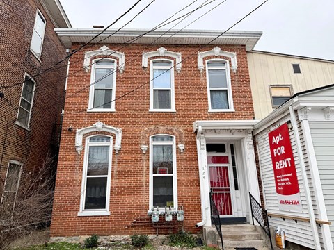 A red brick house with a sign that says "Apt for Rent".