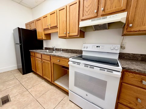 A kitchen with a white stove and black refrigerator.