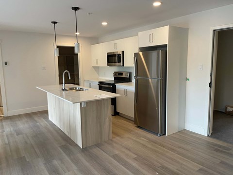 A modern kitchen with a stainless steel refrigerator and a white island.