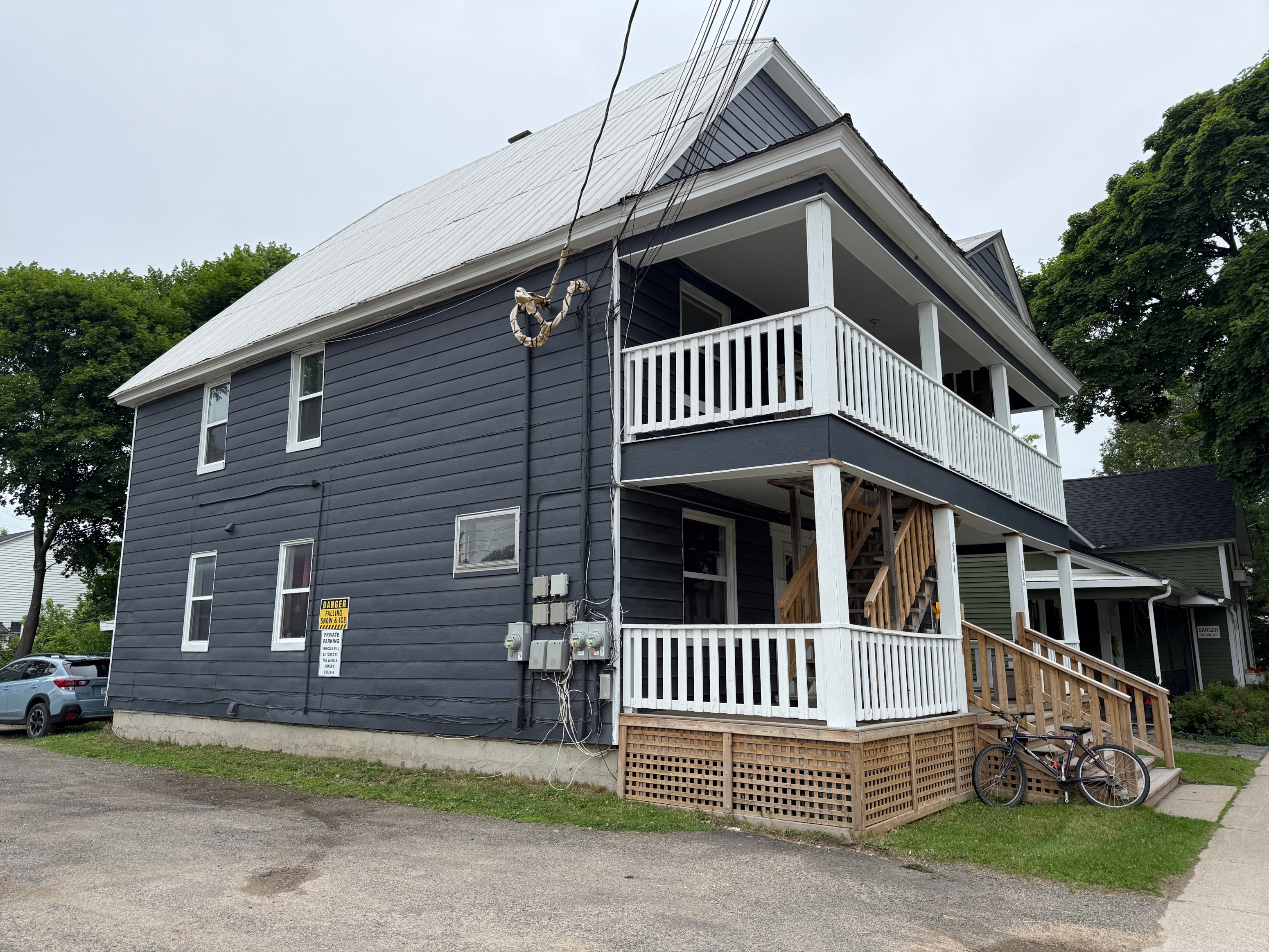 A two-story house with a grey roof and a white porch.