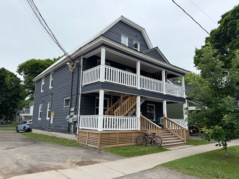 A two-story house with a grey exterior and white railings.