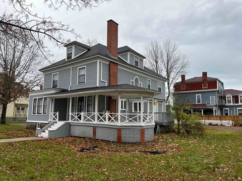 A house with a grey front and a red chimney.