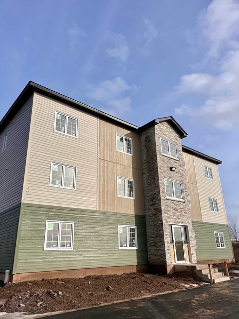 A two-story building with a mix of beige and green siding.