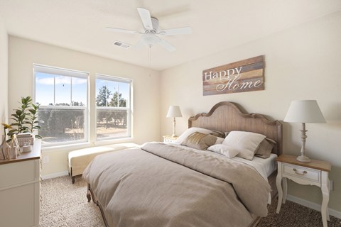 A bedroom with a large bed and a ceiling fan.