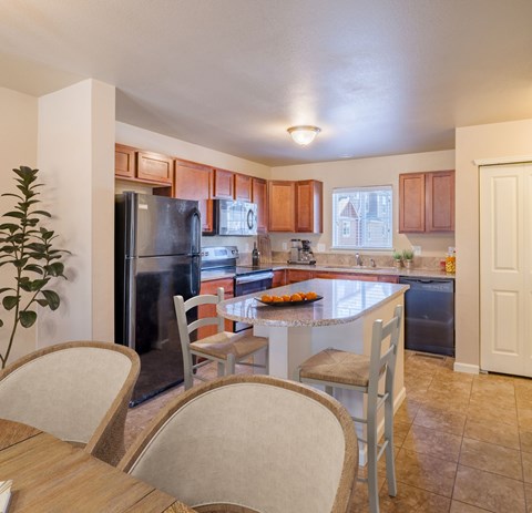 A kitchen with a refrigerator, sink, and dining table.