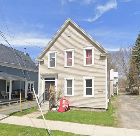 A two-story house with a red flag on the front lawn.