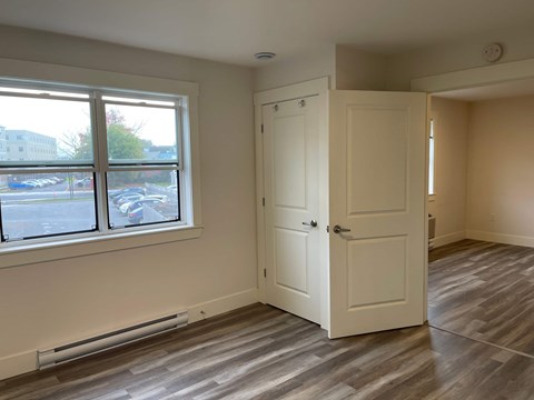 A room with a white door and a window overlooking a parking lot.