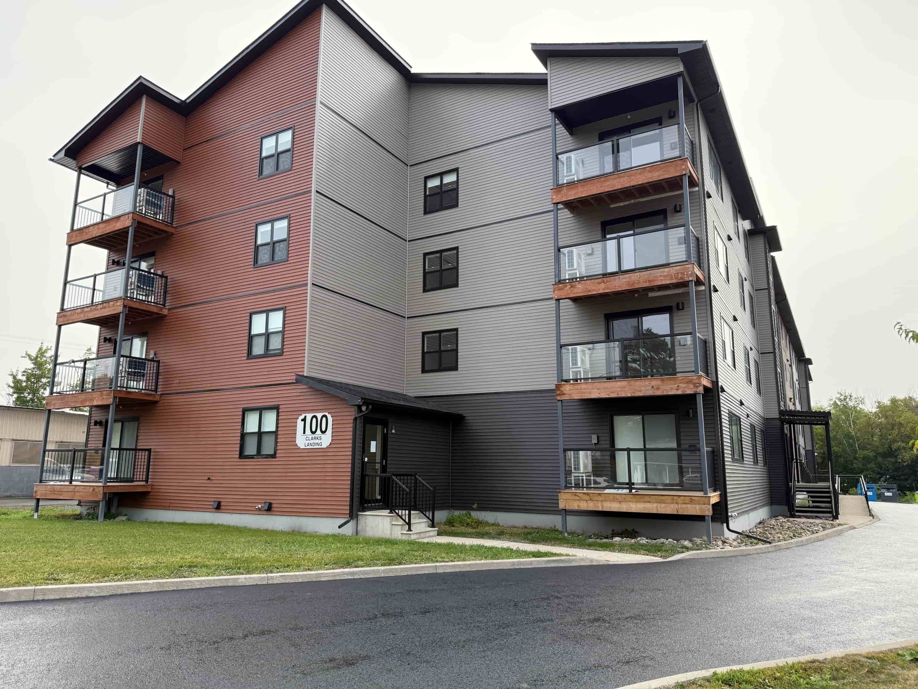 A modern apartment building with balconies and a number 100 on the front door.