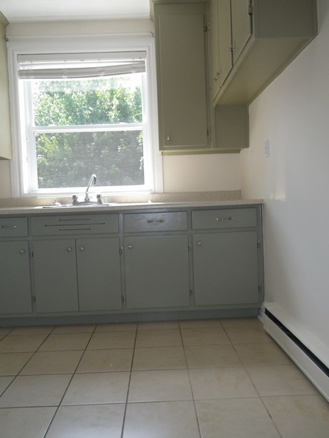A kitchen with grey cabinets and a window.