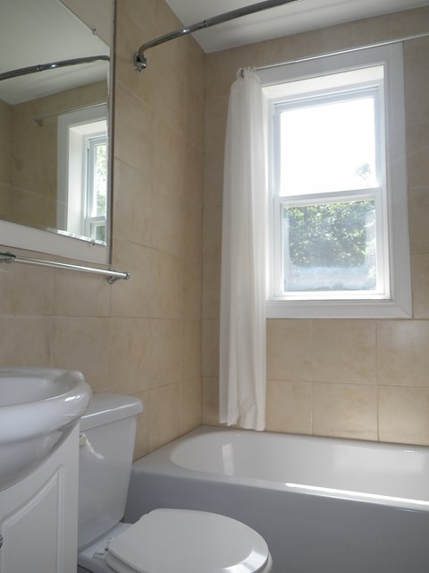 A white toilet sits next to a bathtub in a bathroom.
