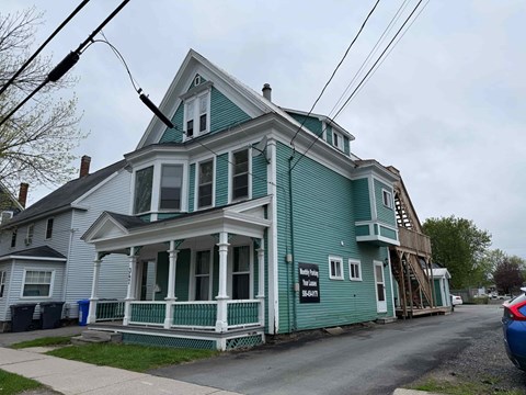 A blue house with a porch and a sign that says "Sold".