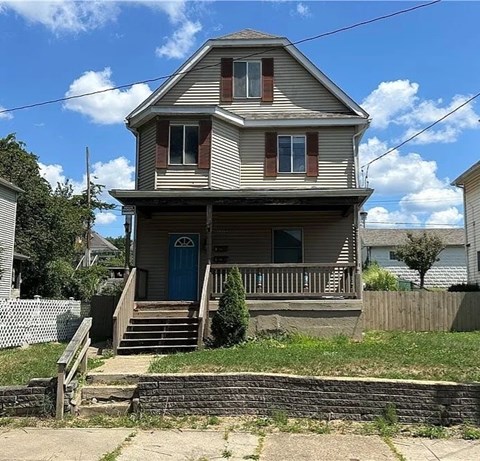 A two-story house with a blue door and a wooden porch.