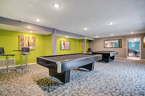 A room with a pool table and two chairs.