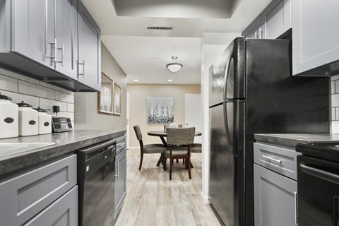 A modern kitchen with a black refrigerator and a dining table with chairs.