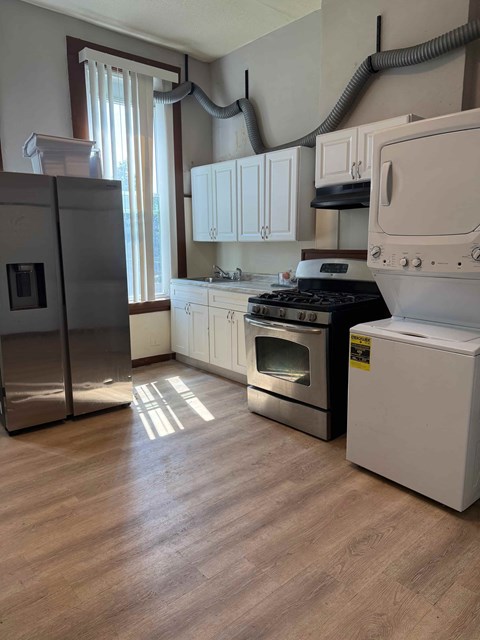 A kitchen with a refrigerator, oven, and stove.