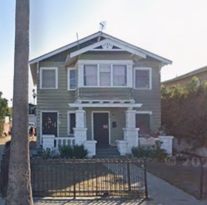 A two-story house with a front porch and a black fence.